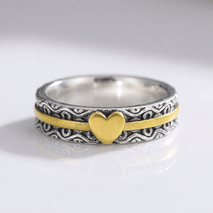 Anillo de banda en oro hecho a mano con corazón, de la marca Rose & Oliver, mostrado en primer plano en la imagen.