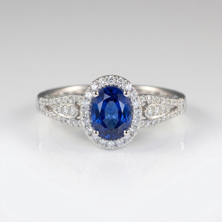 Vintage-Ring Rose & Oliver mit blauem Saphir-Halo und Silberdetails, Hervorhebung für das elegante Design und den strahlenden zentralen Stein.